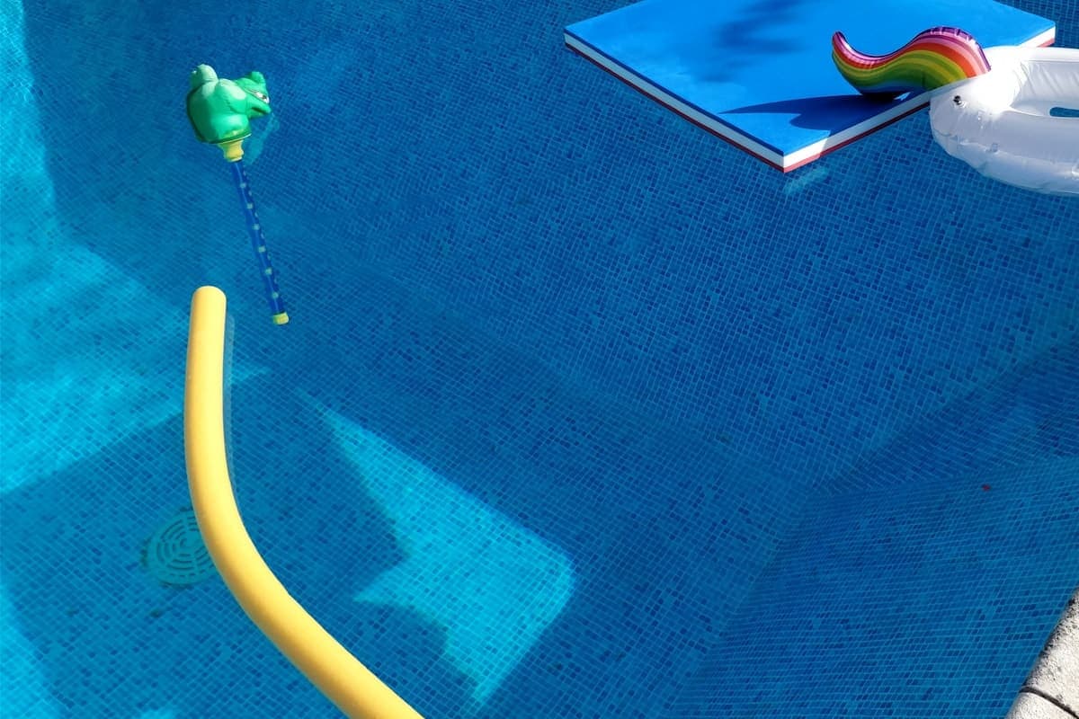 Pool technician checking Houseler on a phone poolside